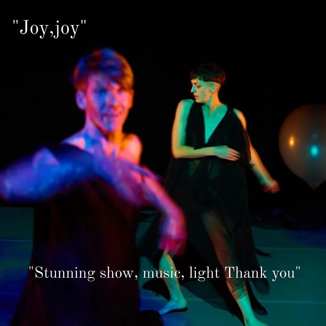 Two dancers in black silk toga-like dresses bathed in purple and green projection. The text says: " Joy, joy. Stunning show, music, light, Thank you."